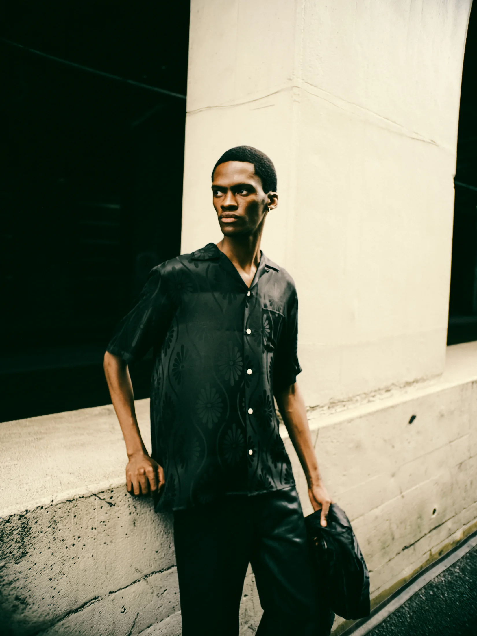 A model wearing a black NIPOALOHA shirt on the street